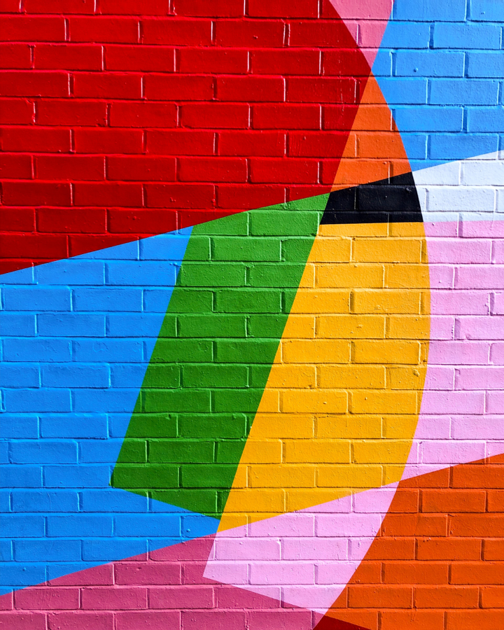 brick wall painted with bright, organic shapes